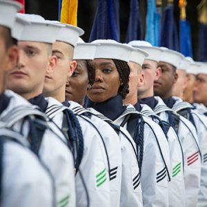 Woman sailor standing in line of male sailors.